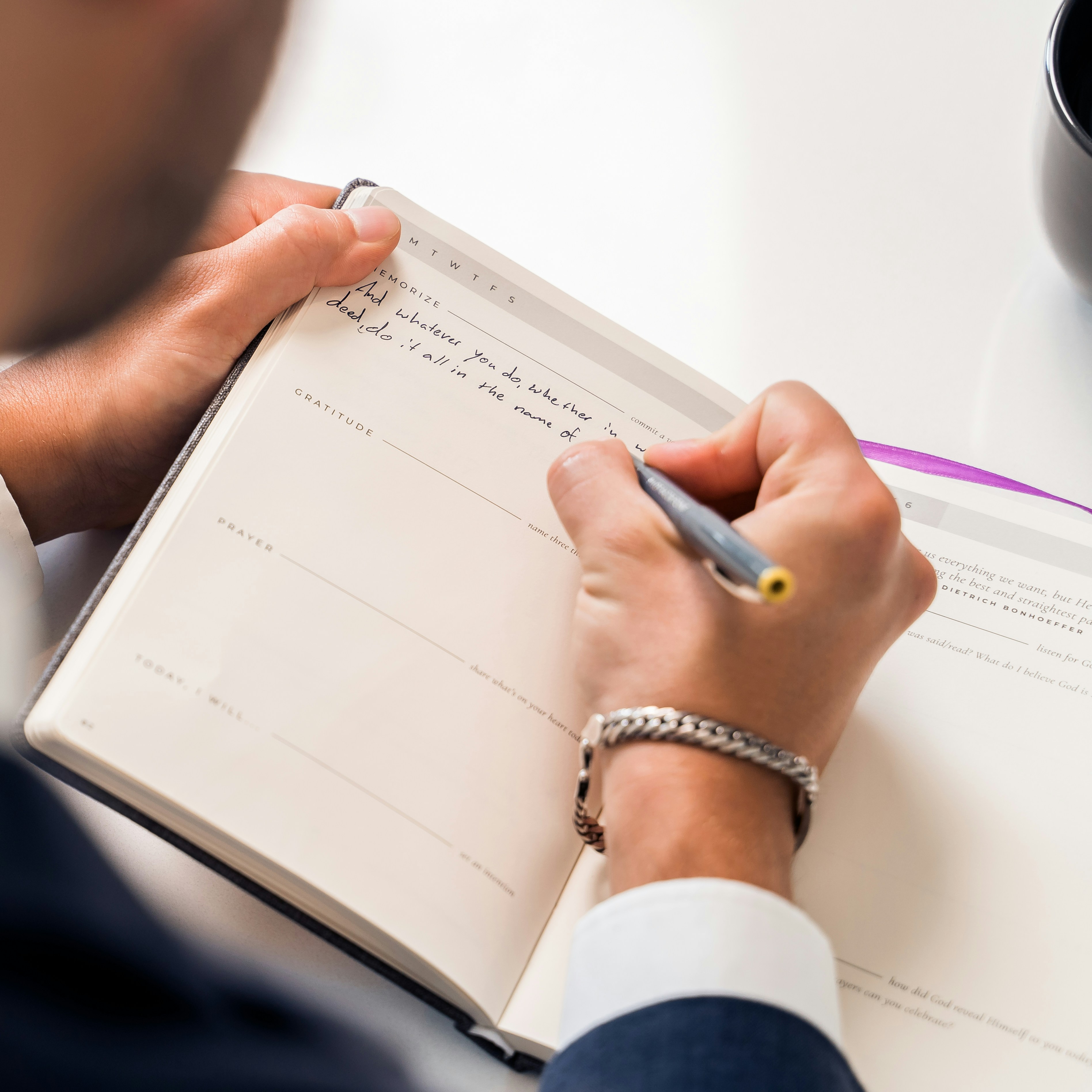 Professional writing notes in an appointment planner at a desk during a business meeting