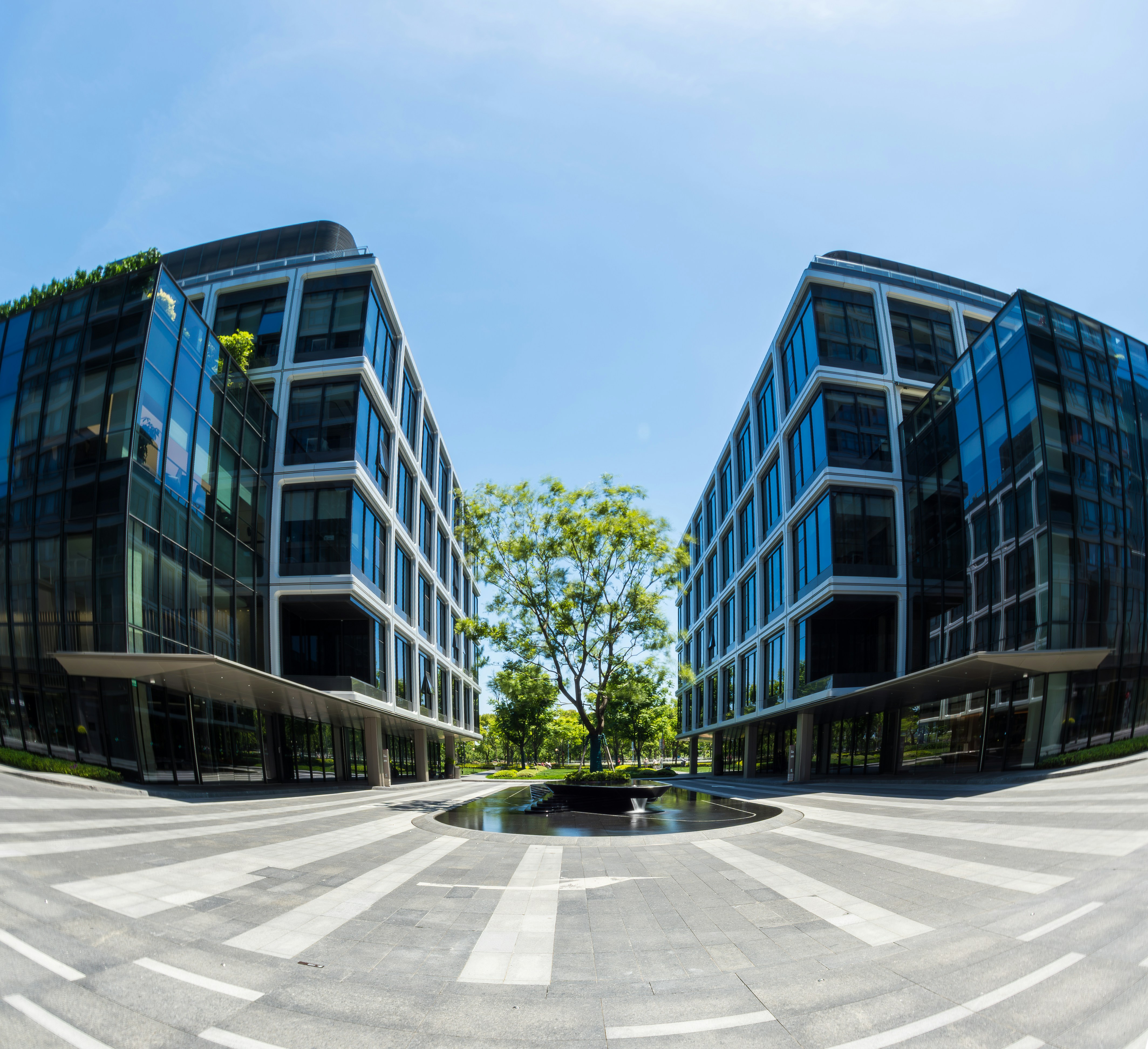 Symmetric view of two modern multi-story glass office buildings with a central courtyard and fountain