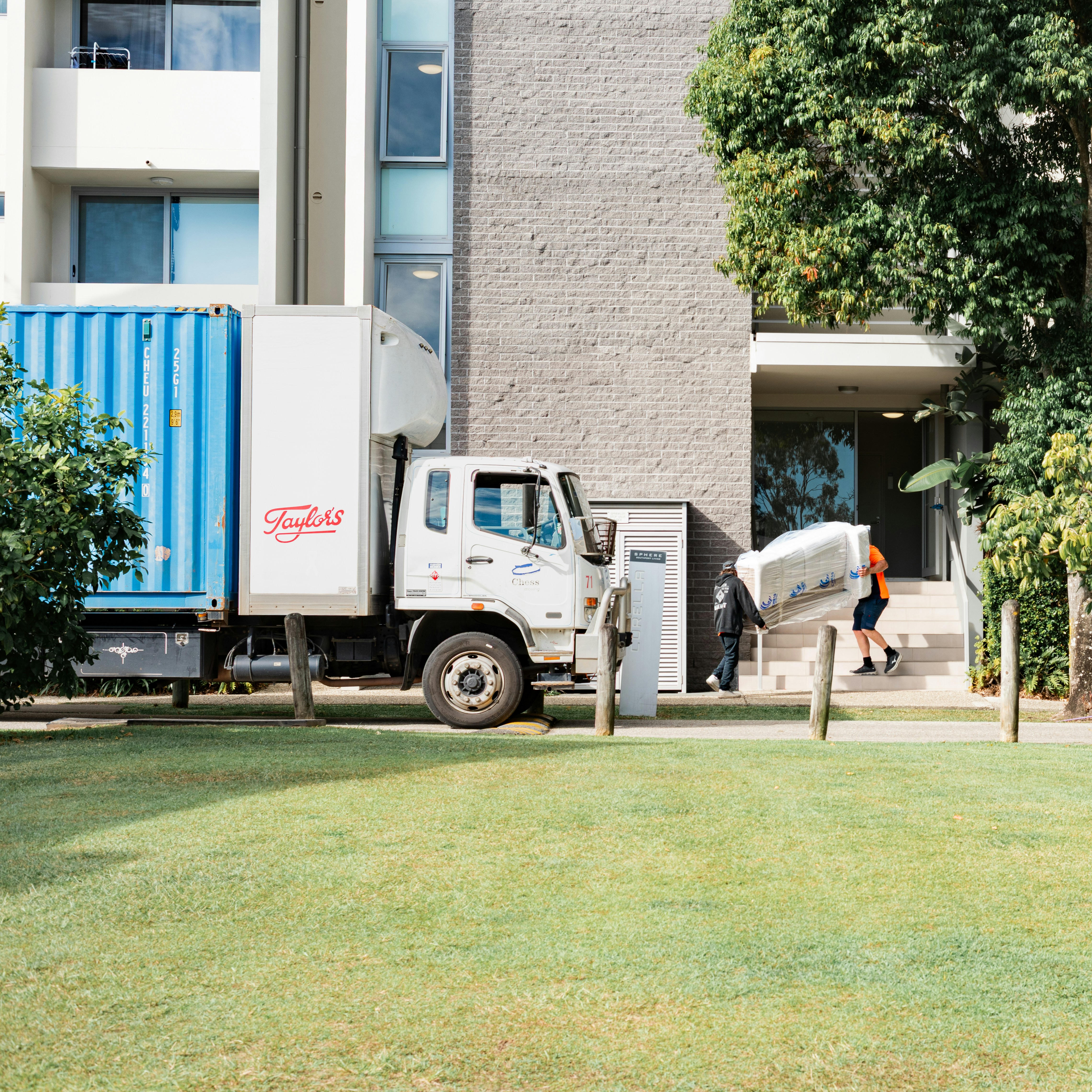 Moving truck parked outside a residential building with crew unloading items during a property service call